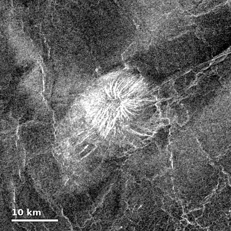 Grayscale Magellan radar image of a Venusian volcanic feature, showing a bright cone with radial lava flows visible in the radar backscatter, with a 10km scale bar