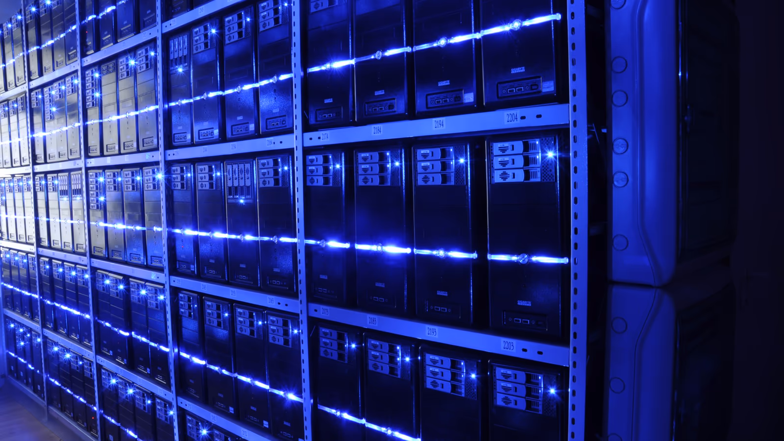 Rows of illuminated server racks in a data centre, representing the scale of compute infrastructure required to train a trillion-parameter AI model
