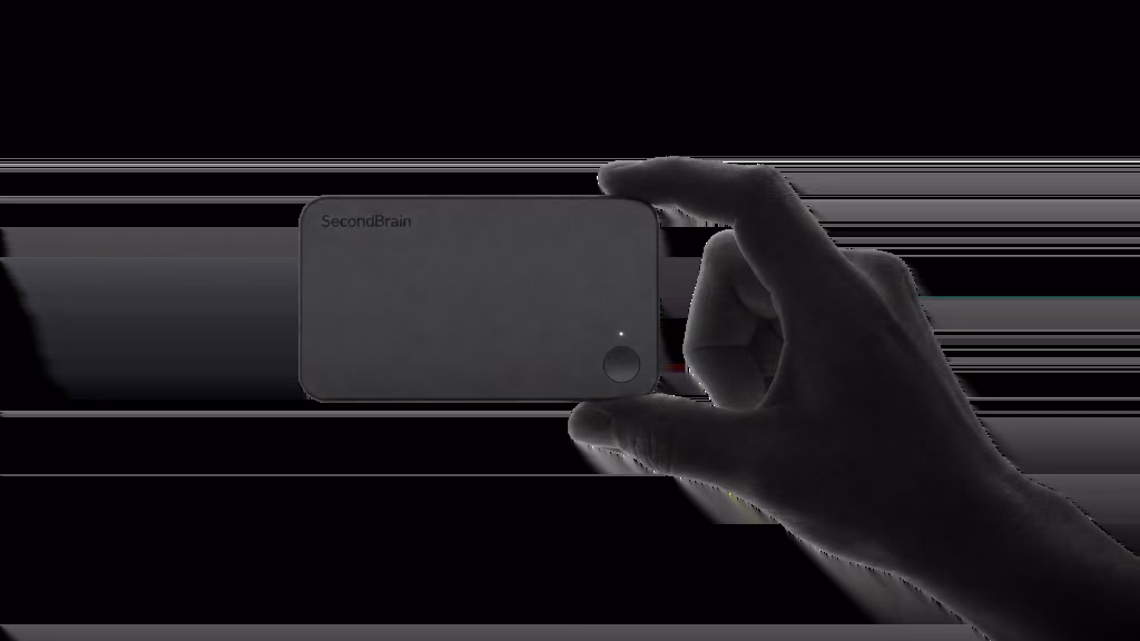 Silhouette of a hand holding the Genspark SecondBrain Note, a thin black card-sized voice recorder with a small status light and record button.