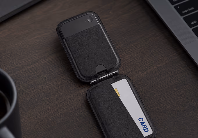 The SecondBrain Note's leather MagSafe wallet open flat, showing its card slot on a desk next to a laptop and a coffee cup.