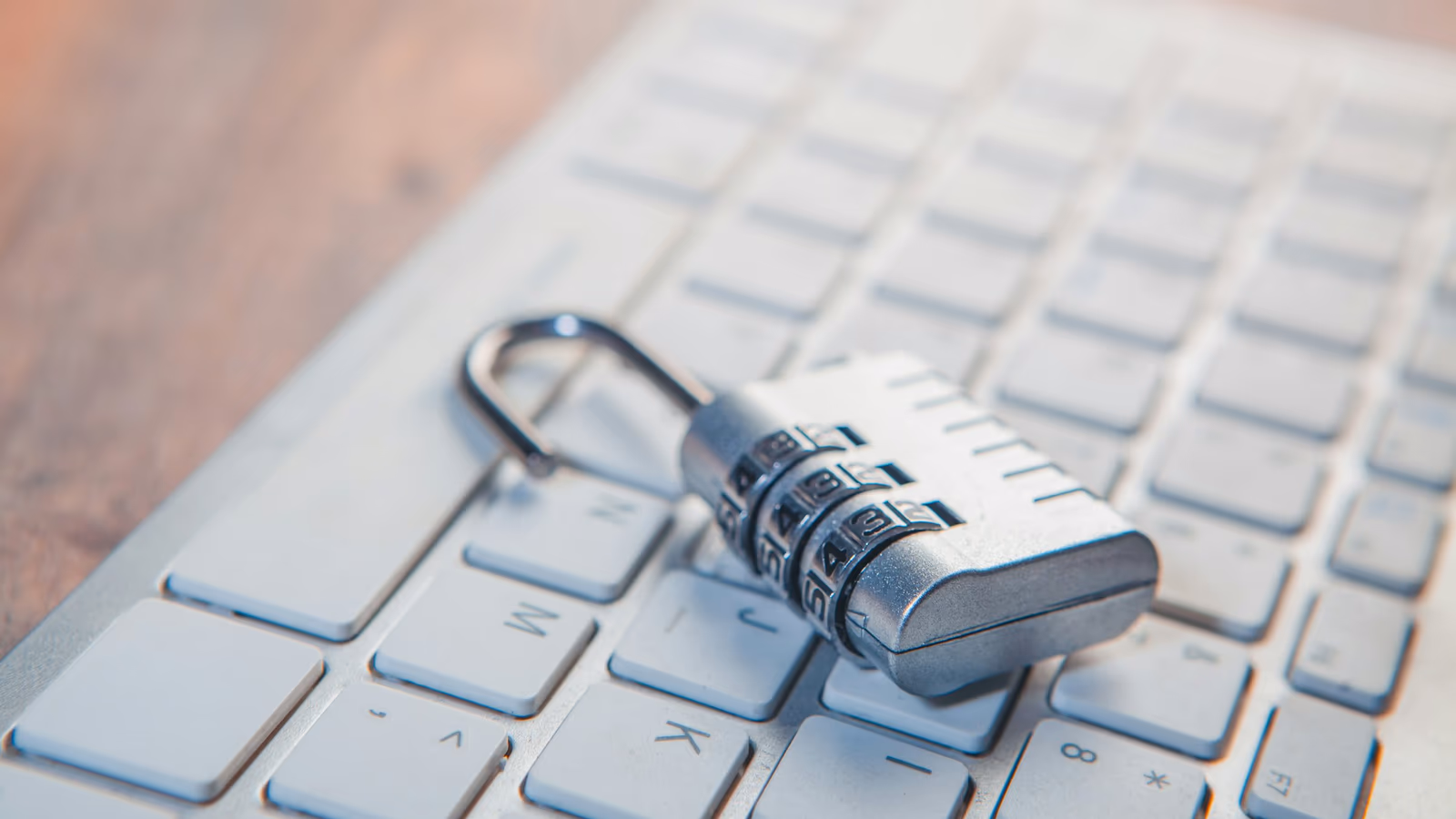An open combination padlock resting on a computer keyboard, symbolising a broken security containment boundary