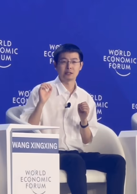 Wang Xingxing, founder and CEO of Unitree, speaking on stage at a World Economic Forum panel, seated behind a name placard reading 'Wang Xingxing'.
